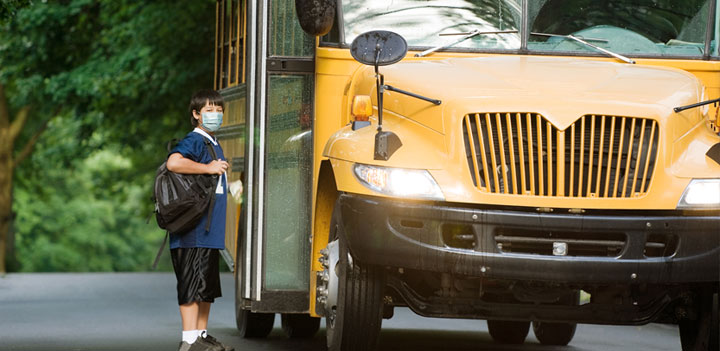 boy in mask getting on bus